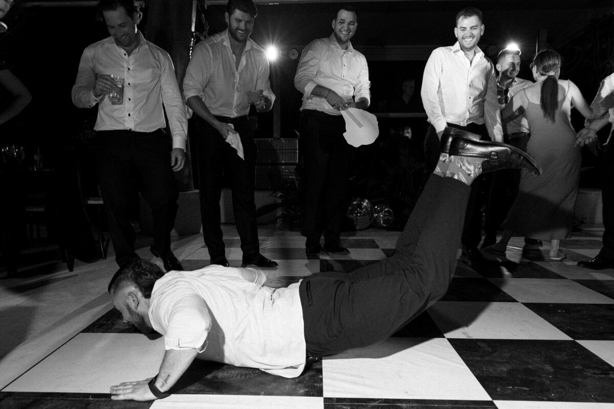 A groomsmen doing the worm on a fun dance floor during the wedding reception in Tulum Mexico at Rosewood Mayakoba, captured by Andrea-Marie Photography