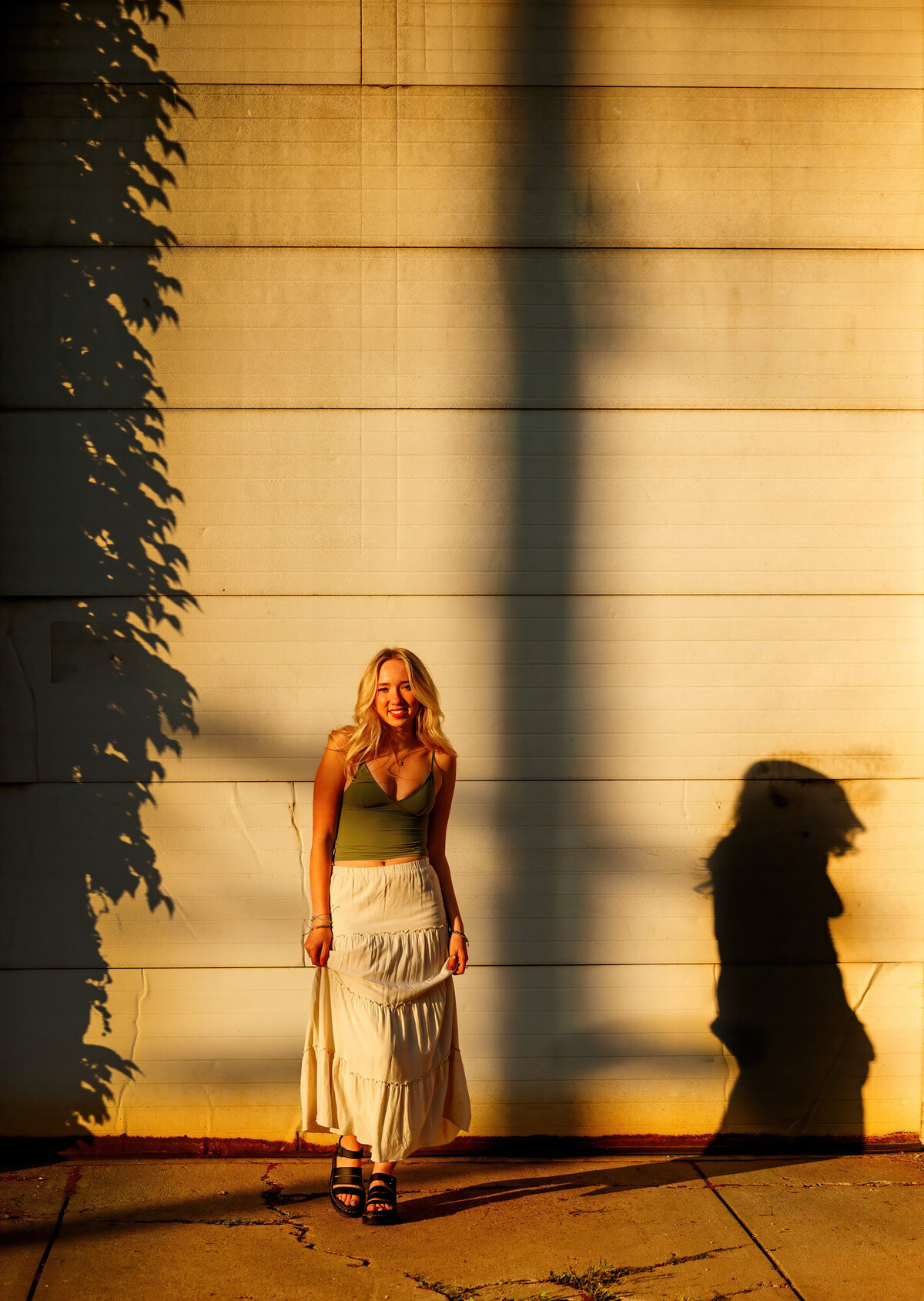 The sun puts a golden cast and shadow of Maria on the white wall.