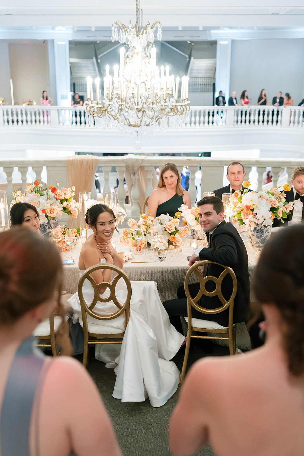 Bride and Groom turned to look at their wedding party giving toasts in their honor at the National Museum of Women in the Arts. 