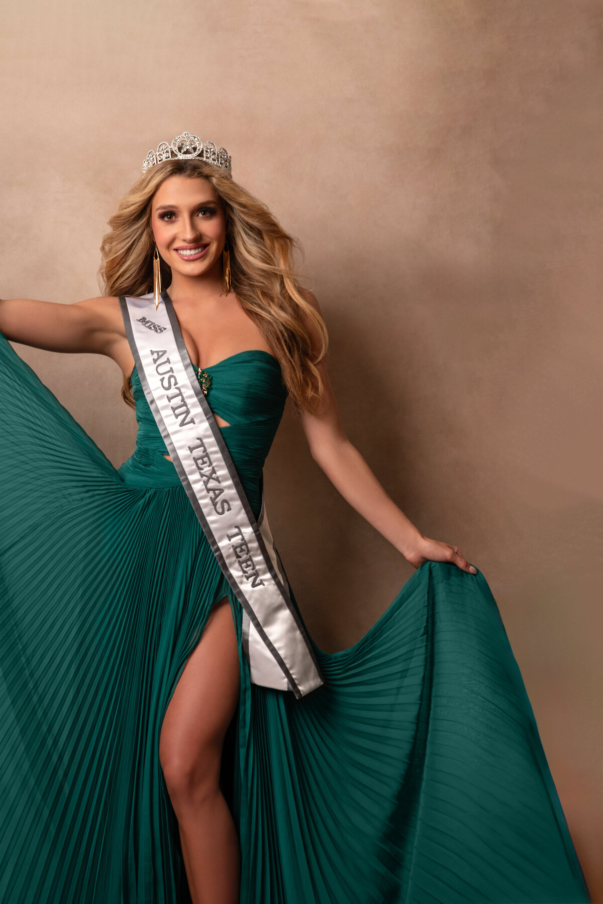 Miss teen Austin wearing a green gown holding it with her hands wearing a tiara and a sash