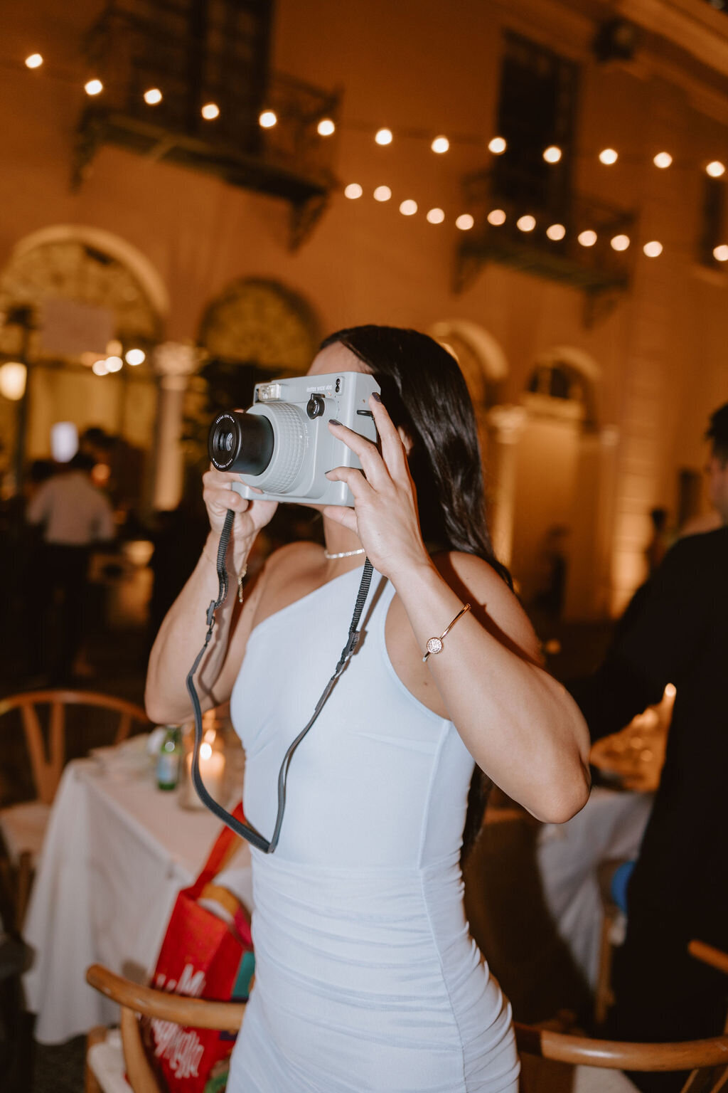 Girl taking photo with poleroid camera and orange glow behind her