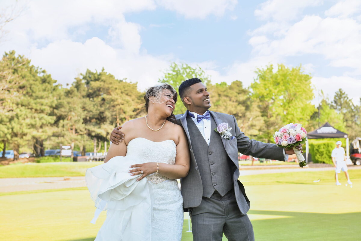 Newlywed couple walking arm-in-arm on golf course.