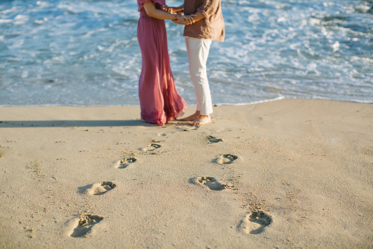 footprints on a beach leading to the couple