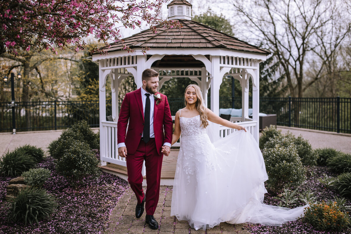 Groom in red suit walking with bride.