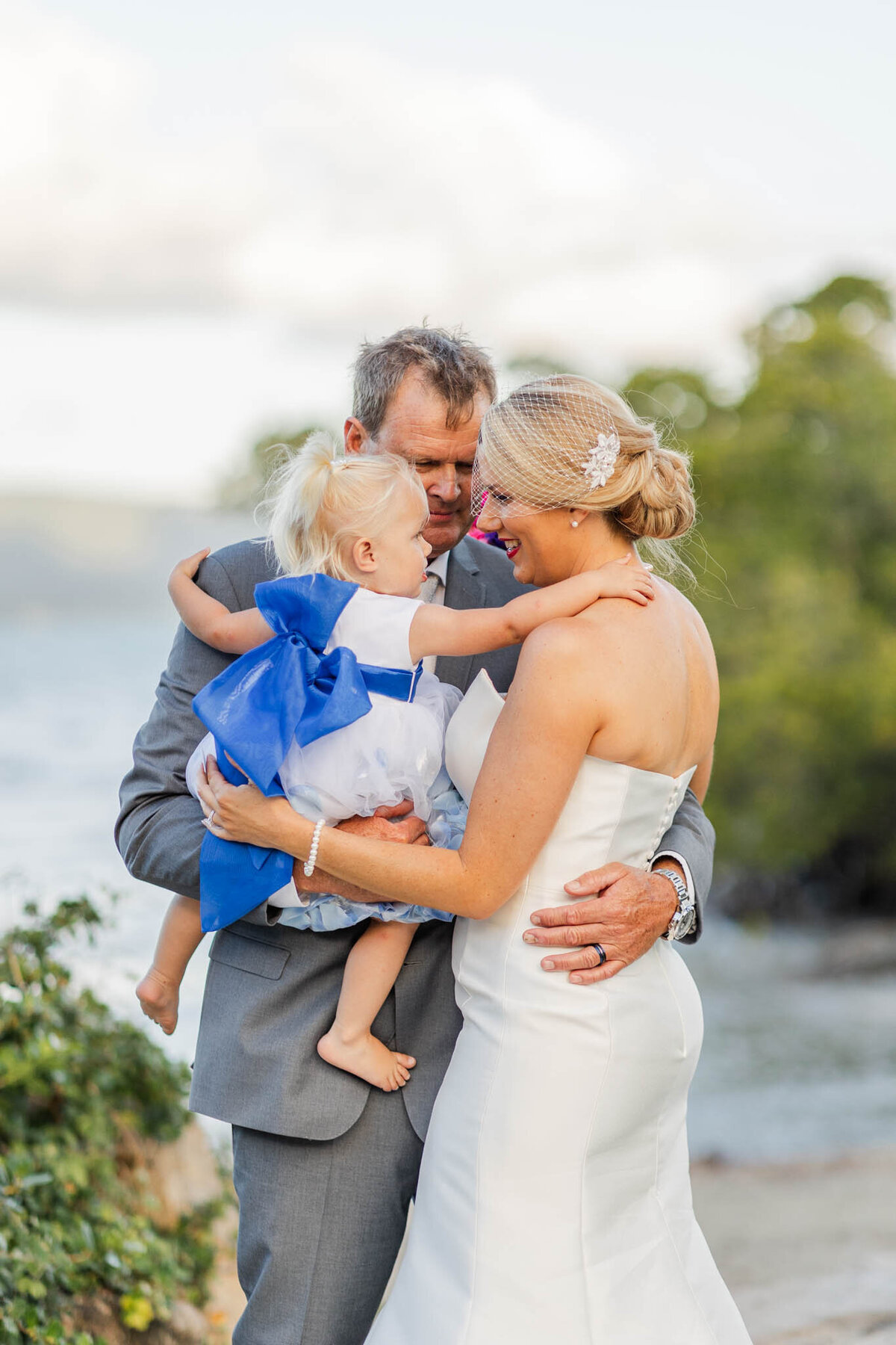 Bride and groom, hold that sweet little girl during portrait time on their wedding day
