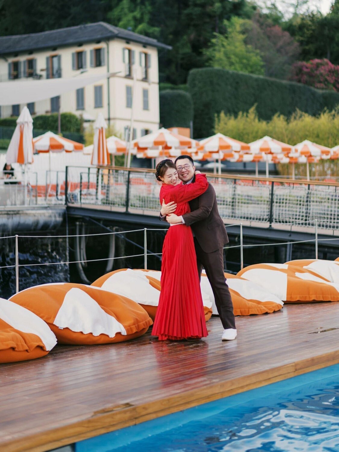 Pool-side Couple portraits during Welcome party at Grand Hotel Tremezzo wedding, bride in red Dior dress, by Lake Como wedding photographer Andreas K. Georgiou  