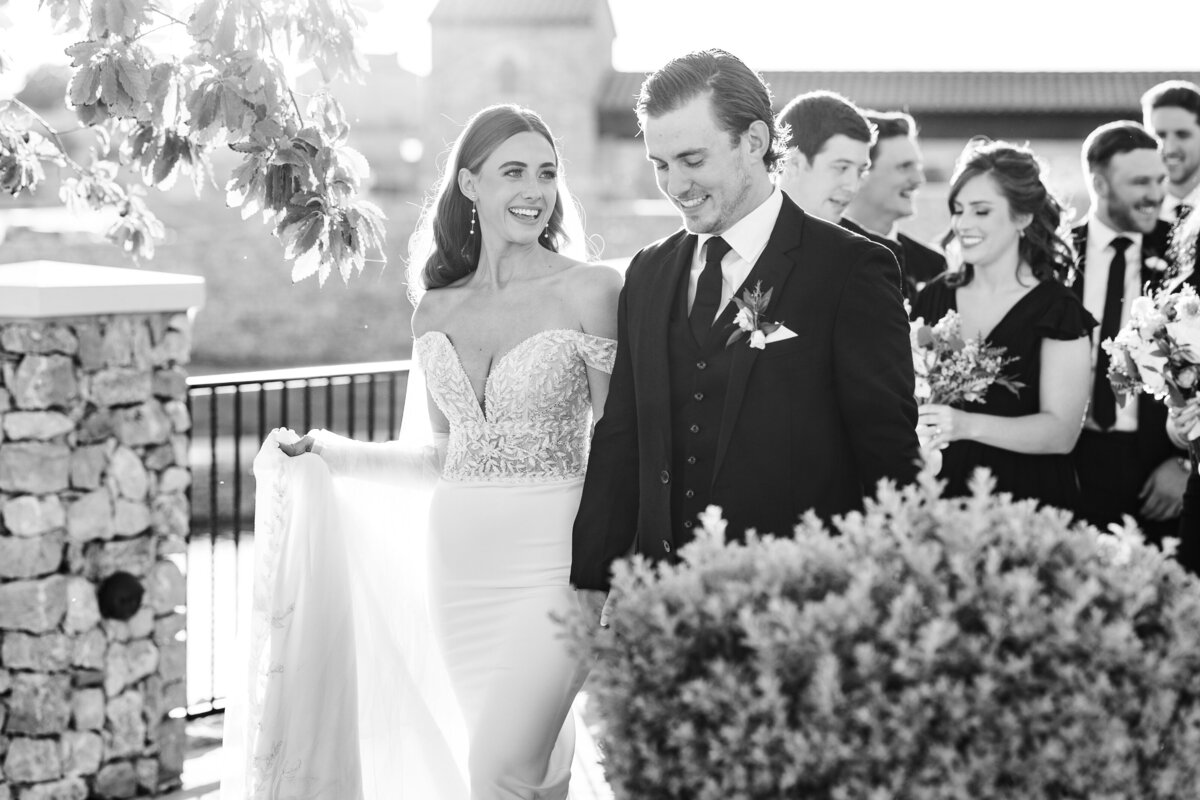 A timeless black and white image of the bride and groom leading their wedding party through a European-style venue in Westlake, a classic DFW wedding scene.