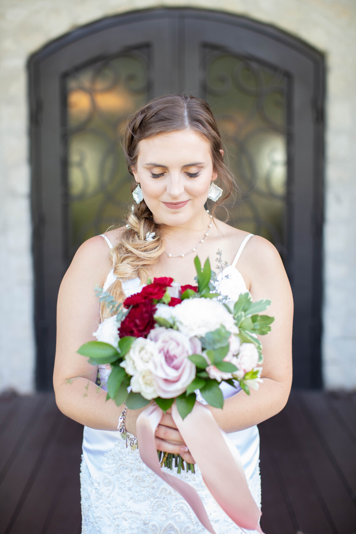 wedding photographer in Texas captures bride looks down at bouquet iron doors of Milestone New Braunfels