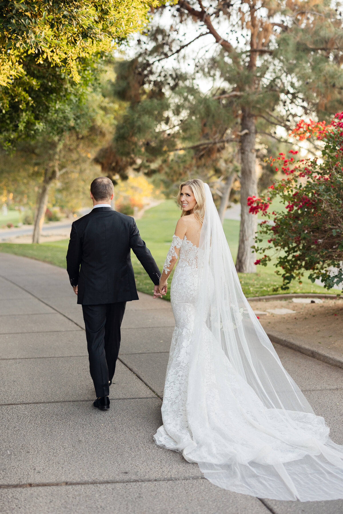 Bride looking over shoulder while walking away with groom taken by Arizona Wedding Photographer and Videographer