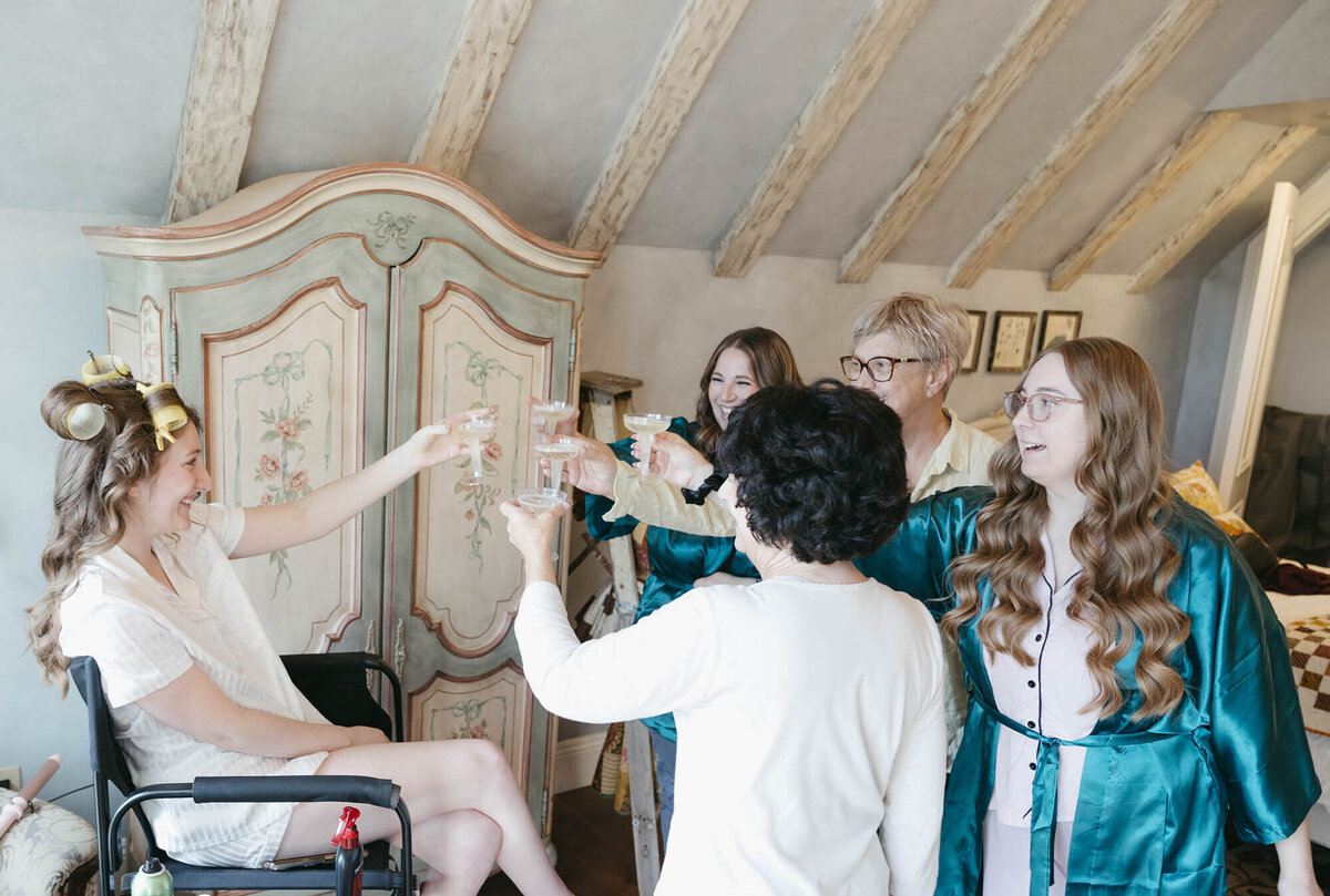 Bridal party cheersing with their glasses, representing the joy and fun everyone partakes in when they have hired Birdie June for wedding planning. 