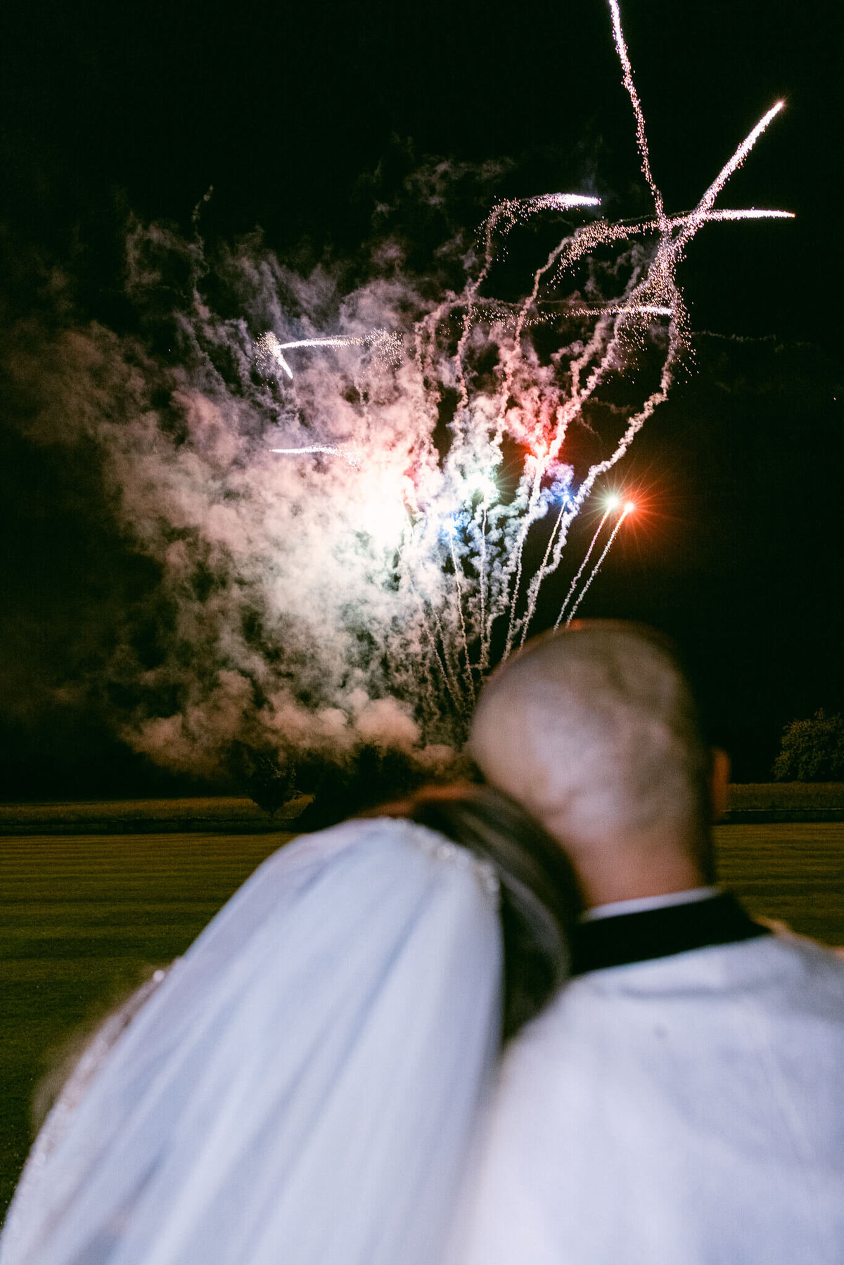 A wedding photo of the couple holding each other while they watch their firework display at Luttrellstown Castle in Ireland