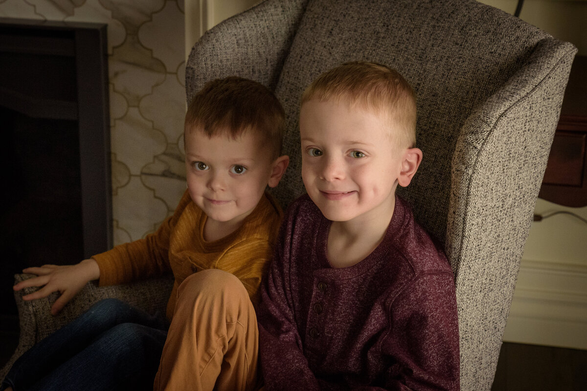 Two young brothers sitting in chair wearing yellow and maroon in their home in Green Bay, Wisconsin.