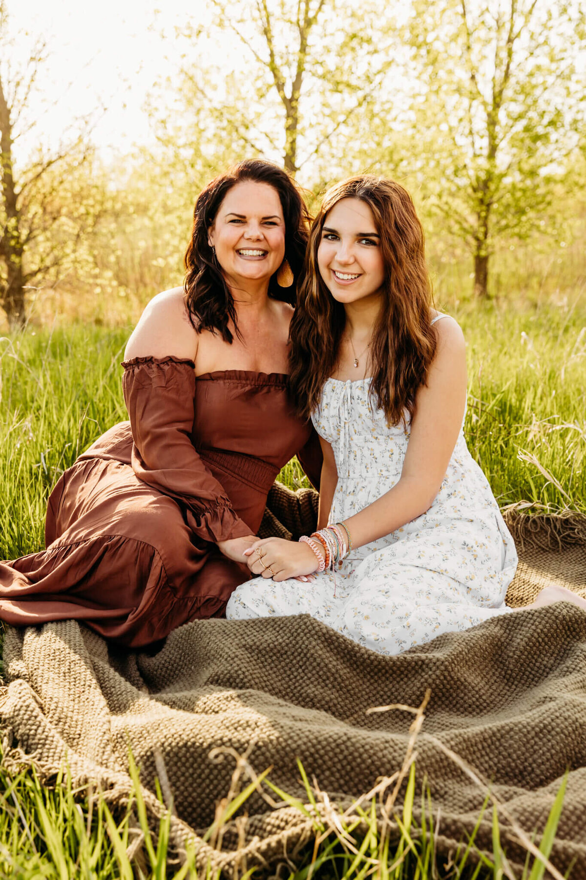 brunette mother and brunette teen daughter sitting on a blanket in the grass by Ashley Kalbus Photography