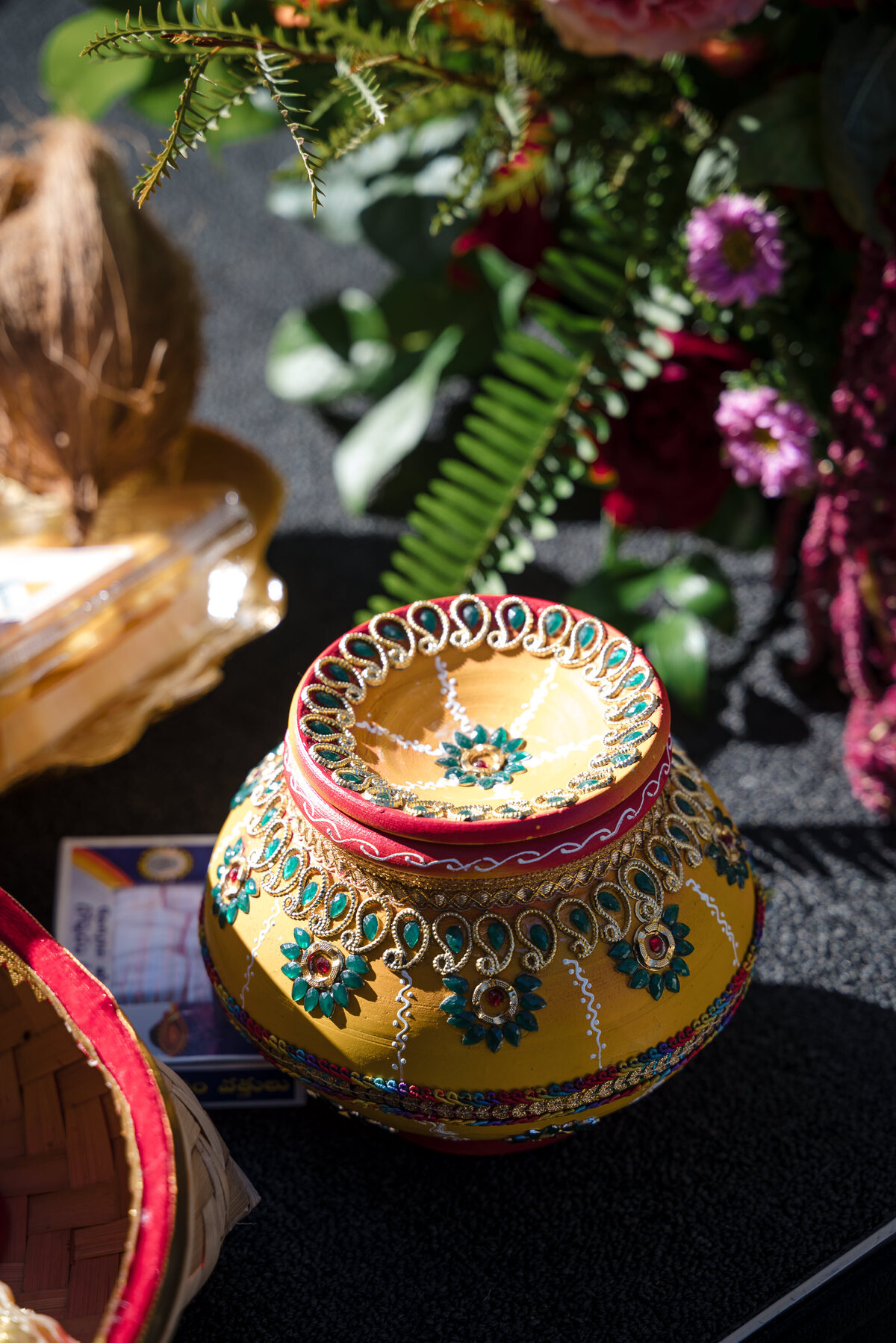 Colorful Indian wedding detail photography at the Grand Bohemian Hotel Charlotte. A beautifully decorated yellow and red ceremonial pot with intricate beadwork and floral designs, captured by a Charlotte Indian wedding photographer specializing in cultural wedding traditions.