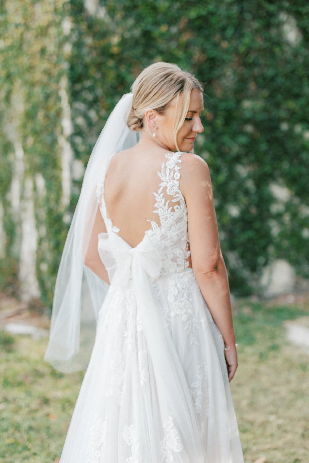 Bride in lace dress with bow-back detail looks over shoulder in Cancun, Mexico.