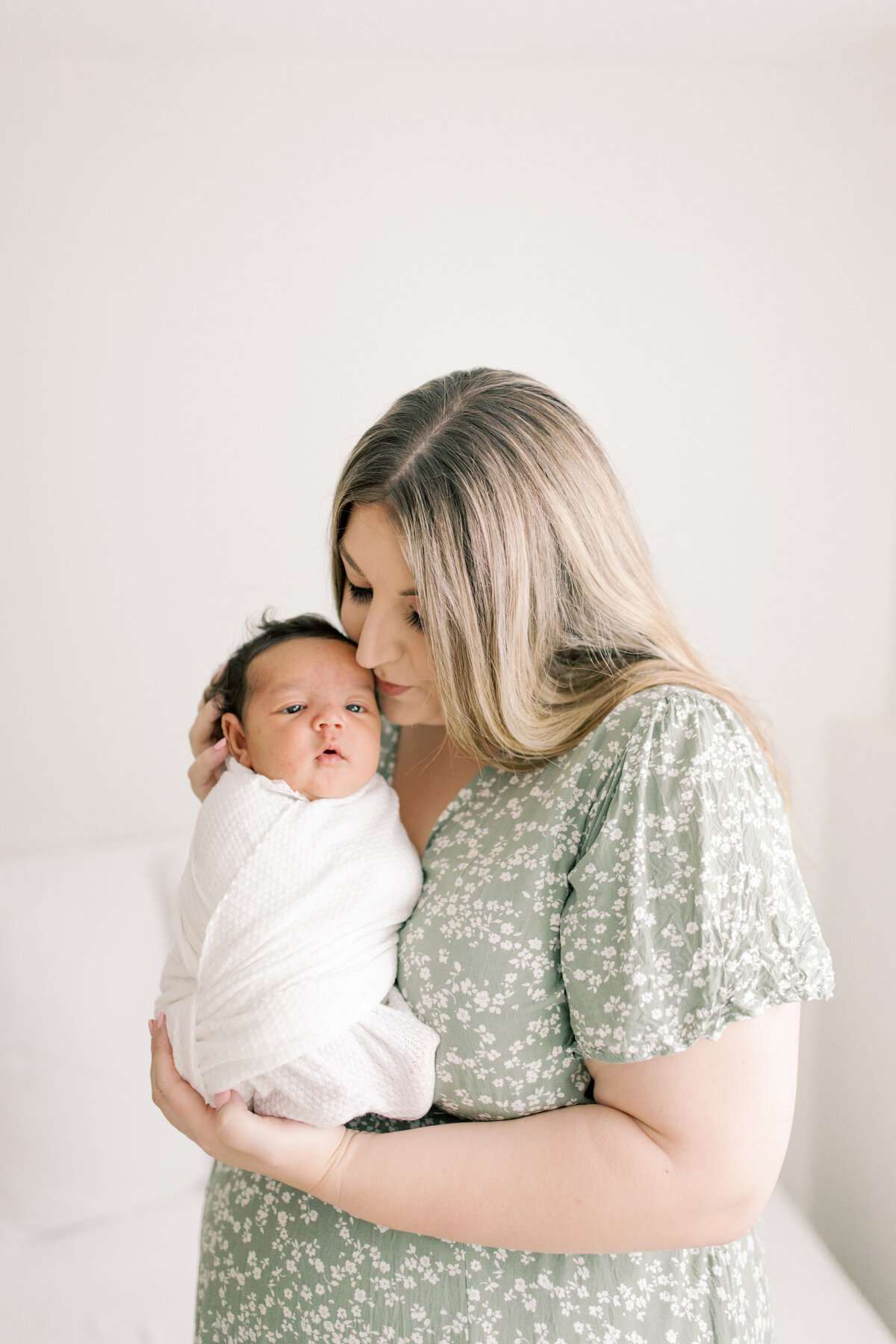 mom kissing newborn son by spokane newborn photographers