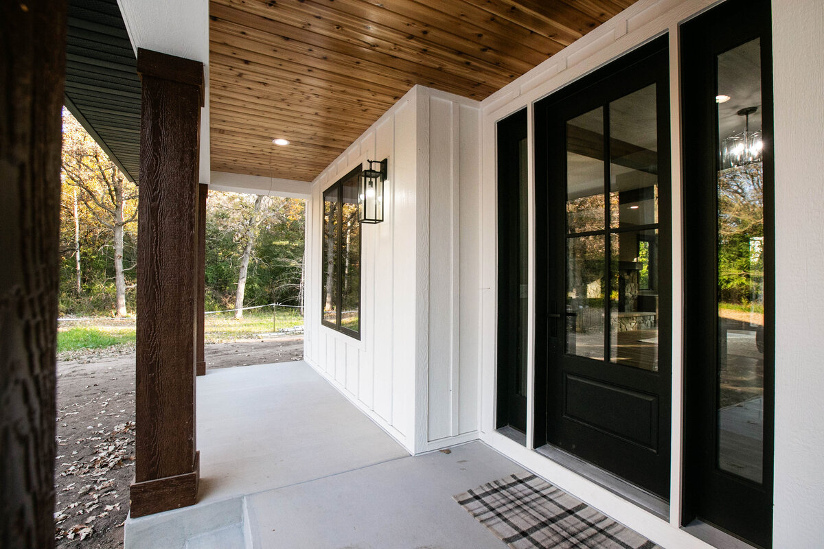 Exterior view of custom home in Big Lake Township, Minnesota with farmhouse details, cream siding, wood pillars and front porch built by Cornerstone Custom Builds