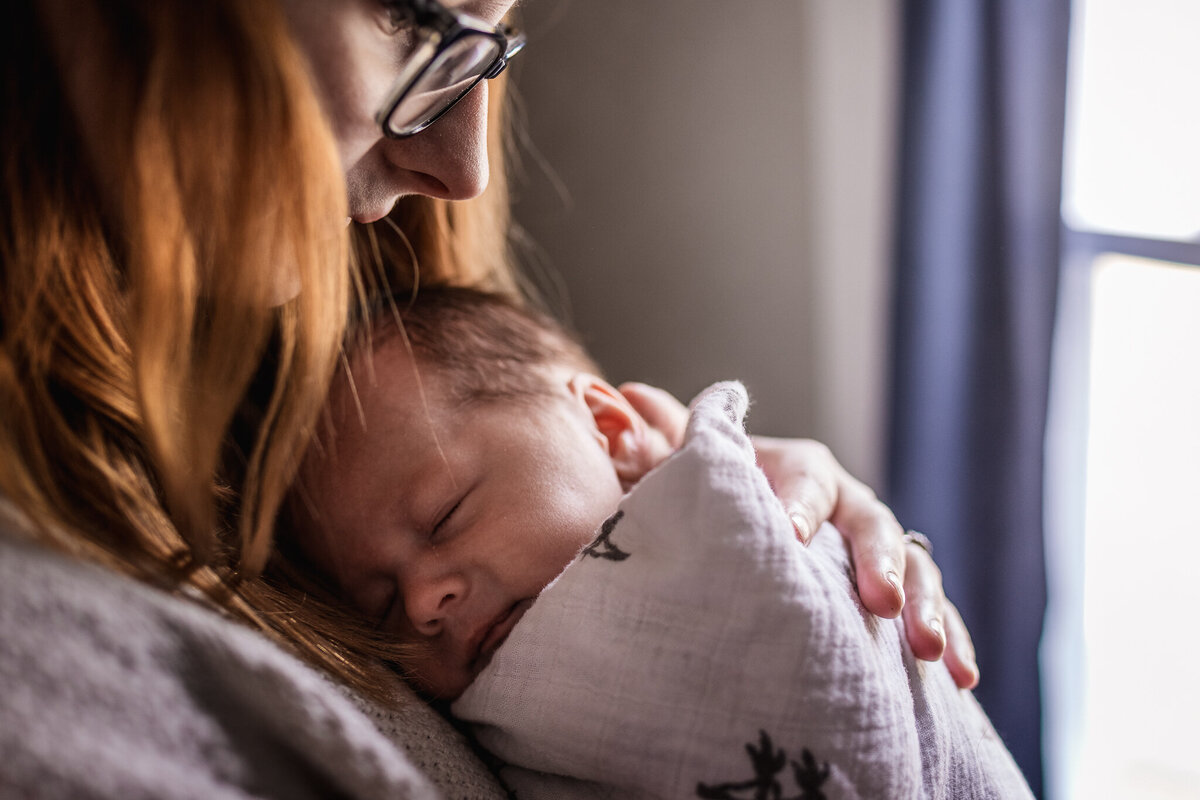 Mom holding baby by a window in an in-home newborn photo session by Lisa Smith Photography