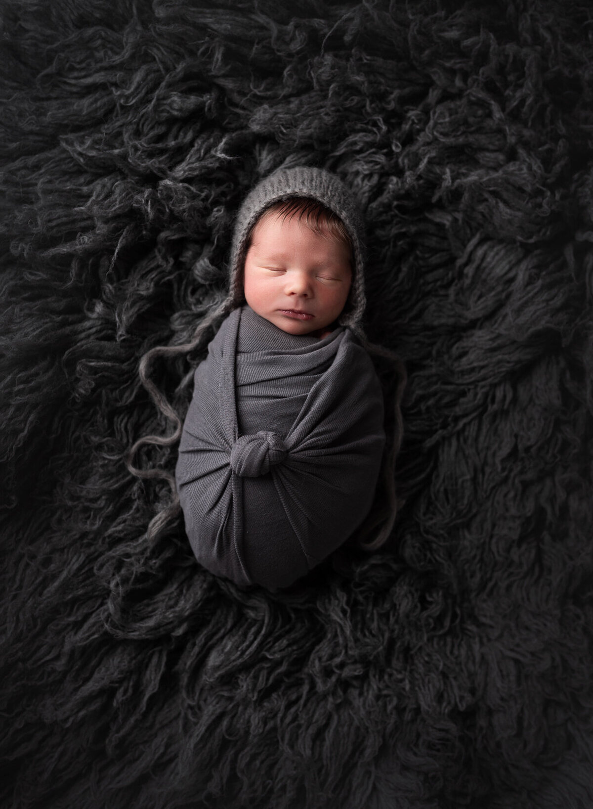 Wrapped newborn in grey furry background by Laura King Photography