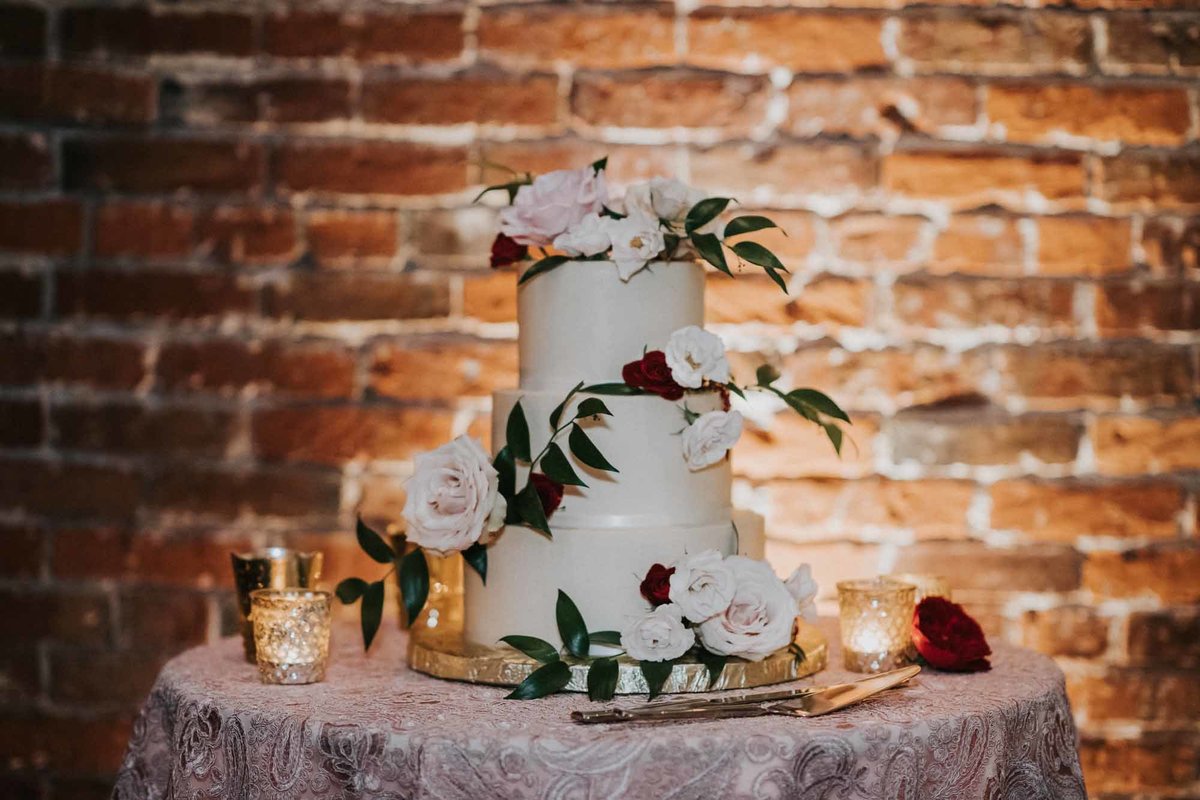 wedding cake with fresh flowers in front of brick wall