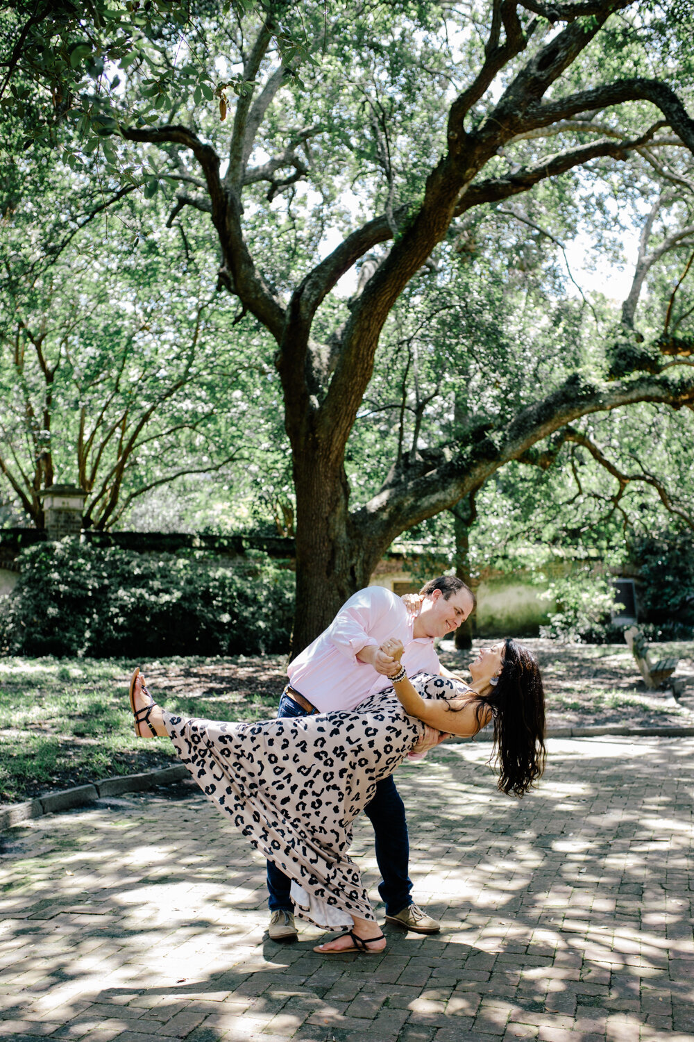 Engaged couple dancing in Washington Park downtown Charleston during engagement photos. Engagement photos captured by Charleston wedding photographer, Stephanie Bailey.