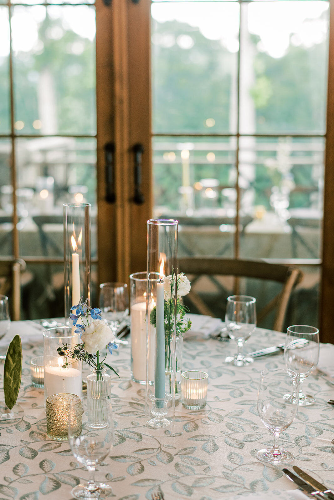 Reception table with light linen, bud vases, and simple white floral accents for an organic elegant aesthetic.