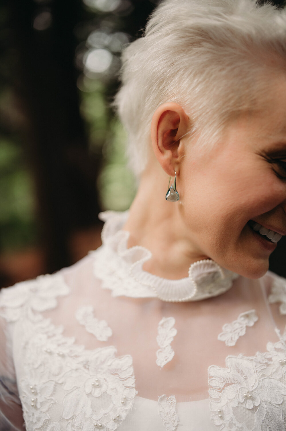 Bride shows off her blue earring with vintage wedding dress for their ohio elopement.