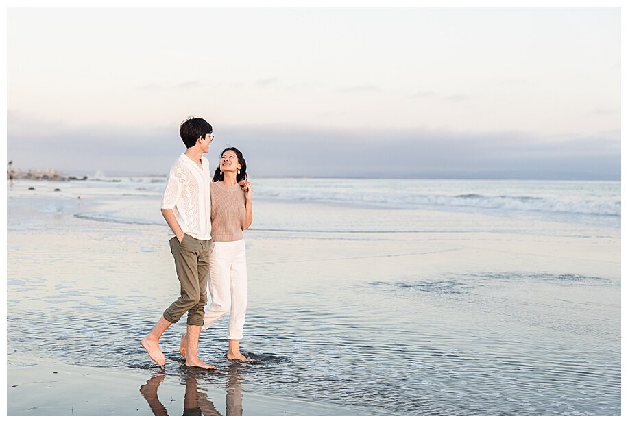 engaged couple walking in ocean at coronado