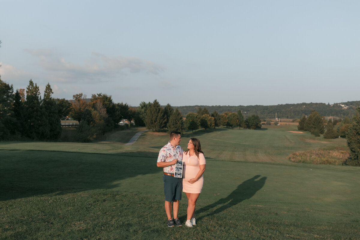 pregnant wife and husband on golf course with ultrasound