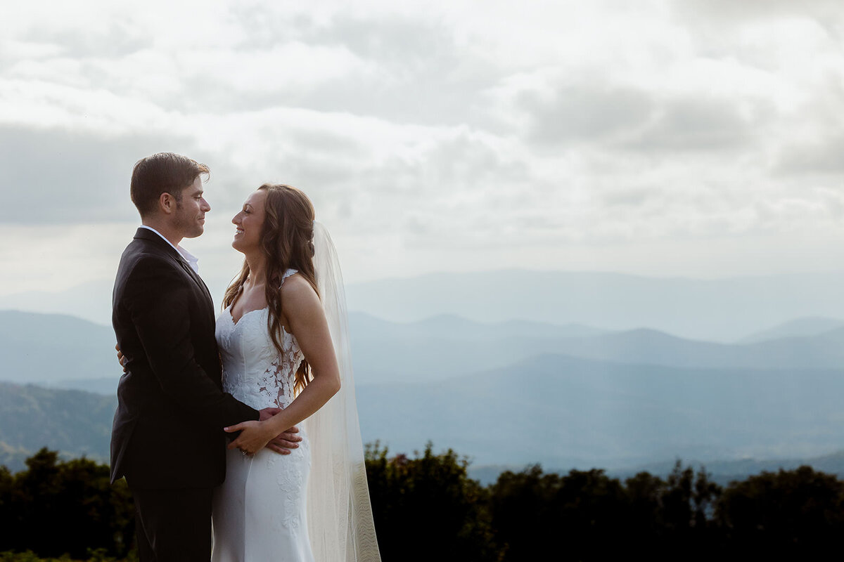A couple standing close together on a mountain overlook