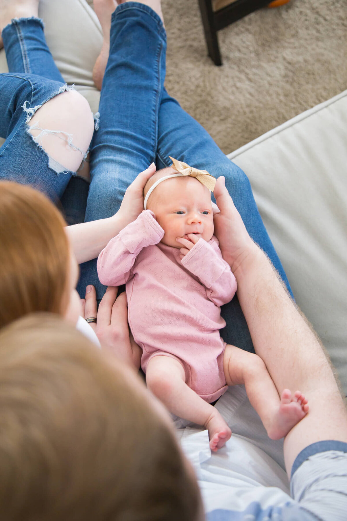 view from above of newborn baby girl in parents laps on a couch