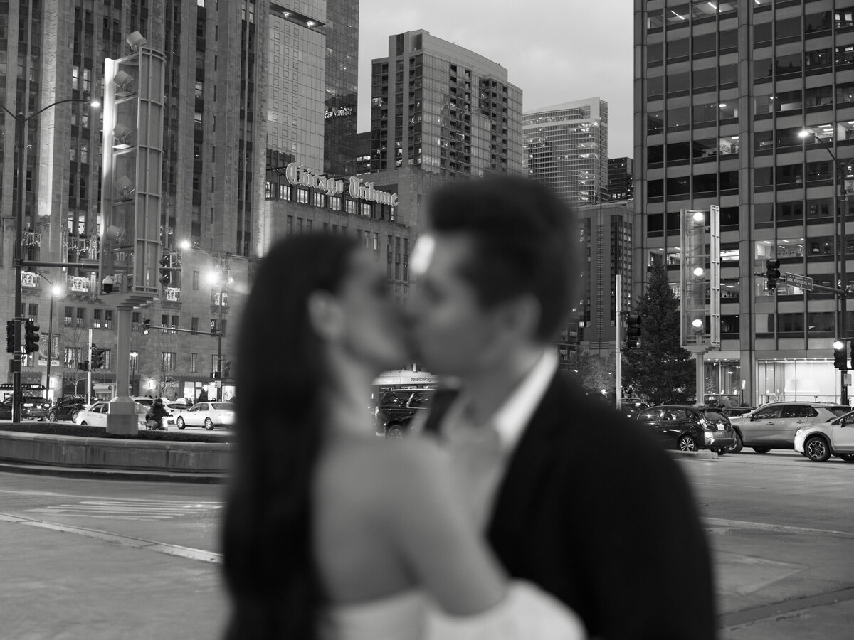 A couple embraces at dusk along Michigan Avenue and the Chicago River, with the city lights creating a romantic and timeless backdrop.