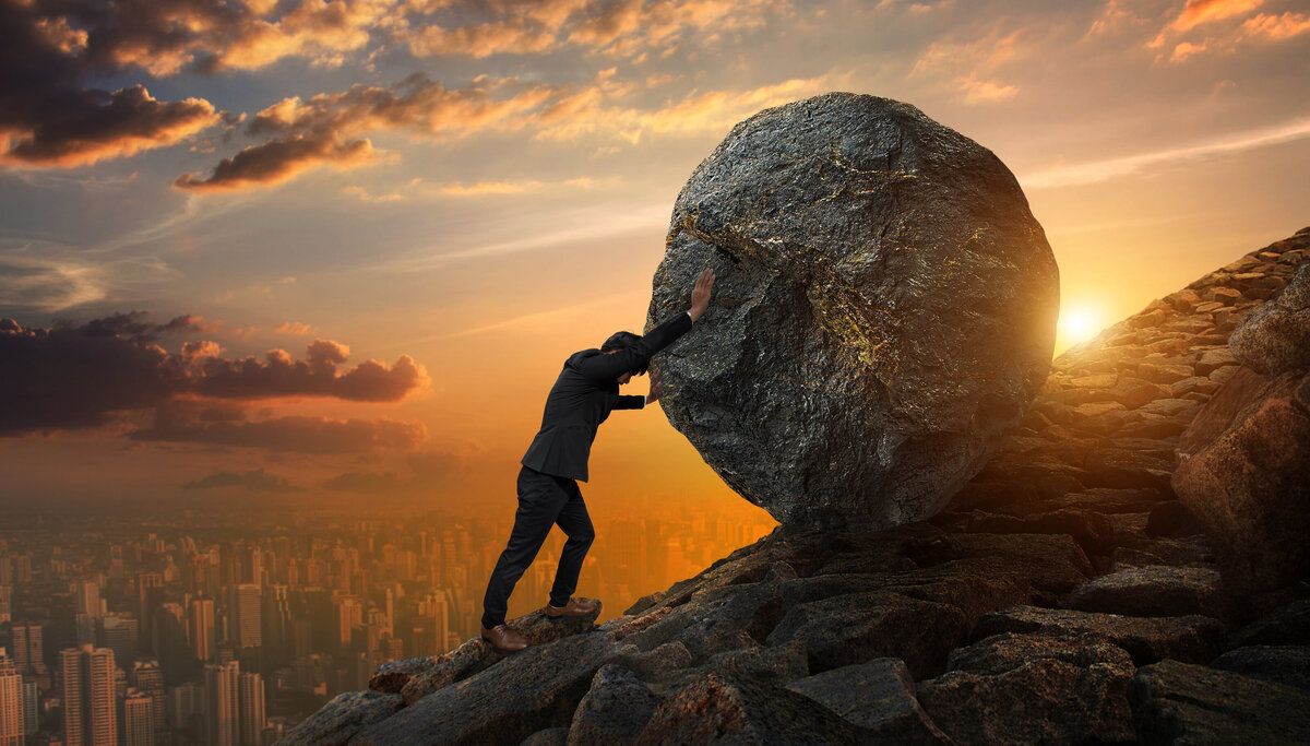 Man pushing a boulder up a mountain