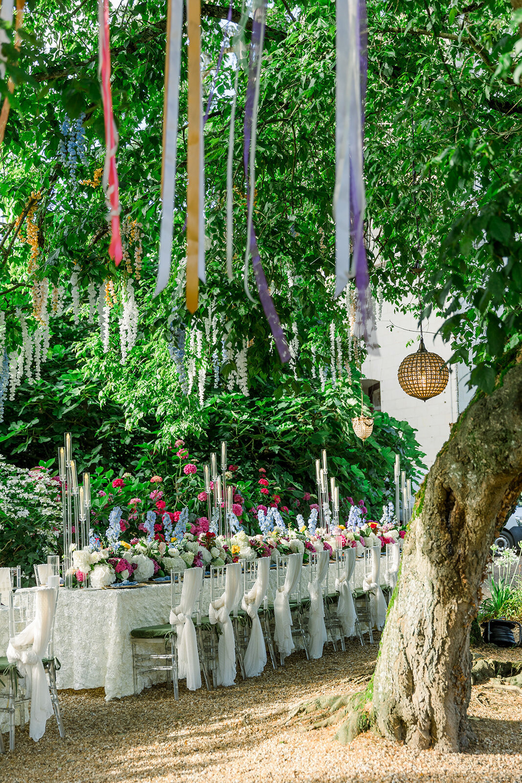 Brightly decorated summer table setting in the secret garden of Château Challain, captured in elegant, romantic fine-art wedding photography.