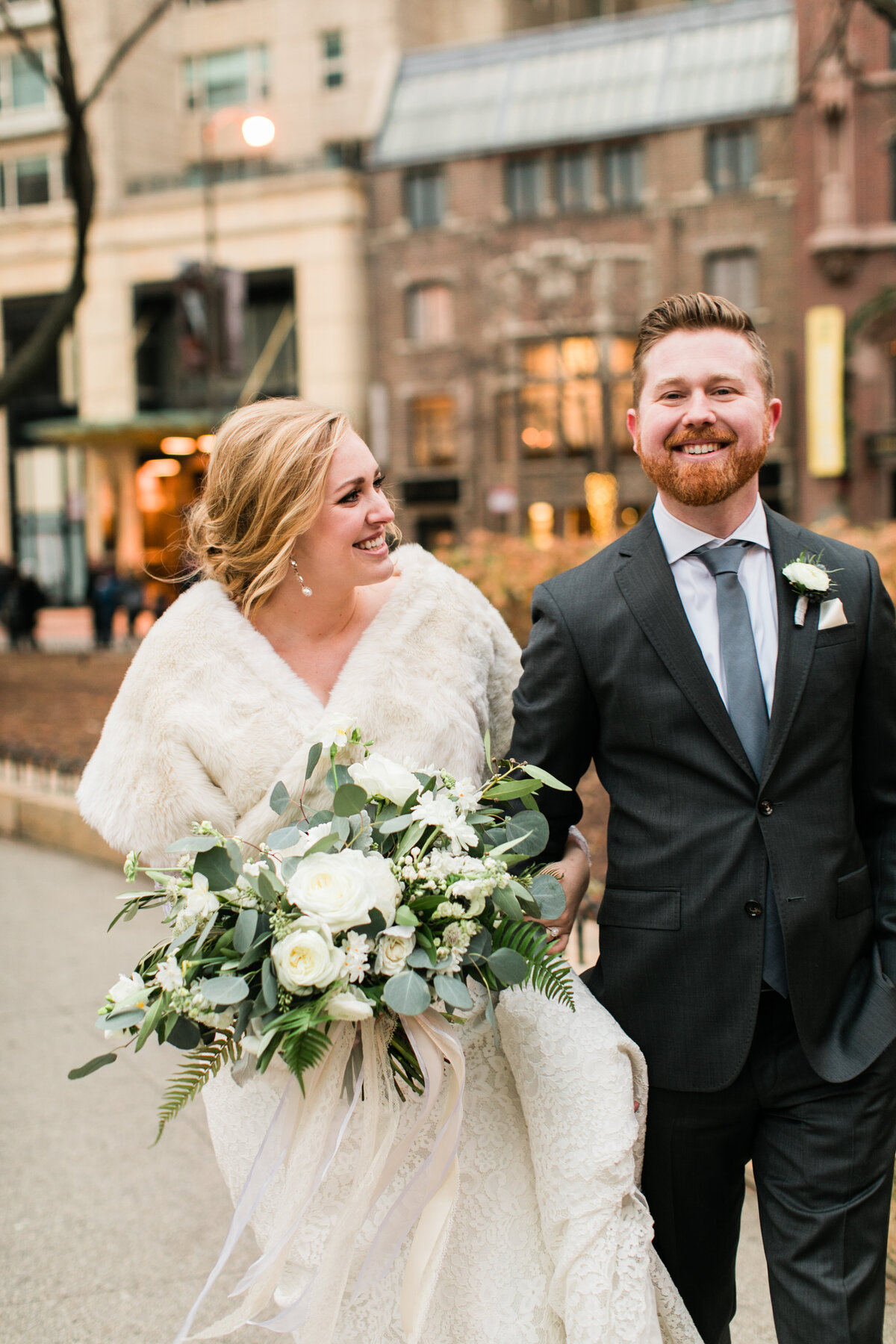 A candid and joyful wedding photo of a bride and groom crossing the street in downtown Chicago, smiling and celebrating their special day.