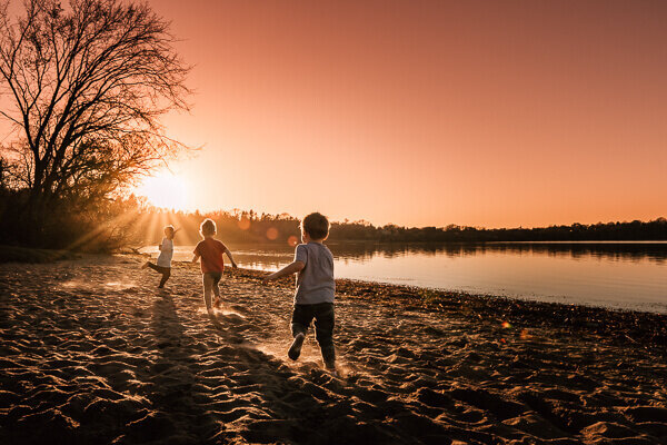Three children frolicking on Lake Harriet South Beach in Minneapolis, Minnesota.