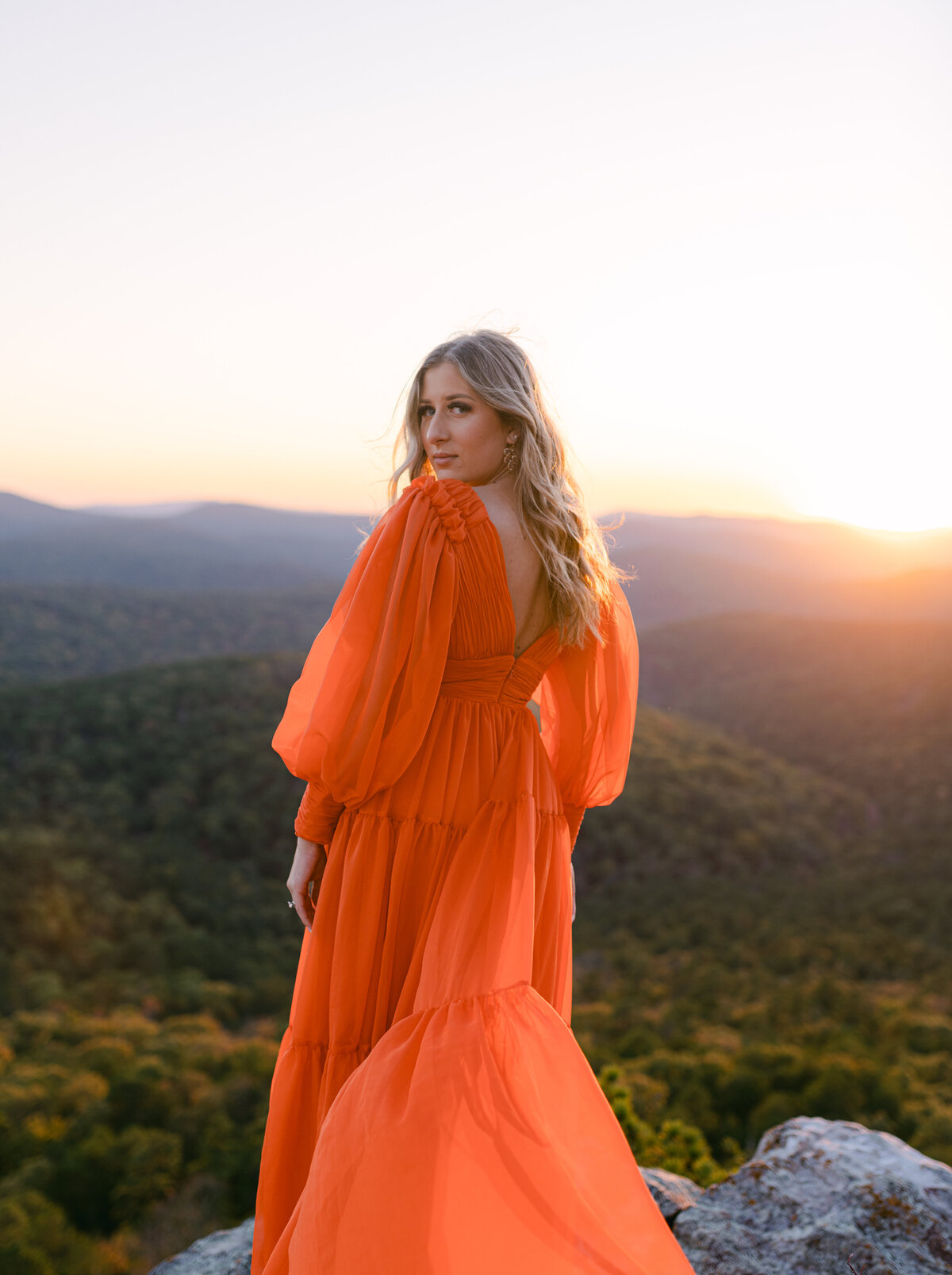 Stunning bride posing for portrait on cliff during sunset