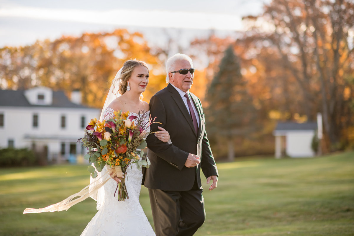 bride and father walking down the aisle with autumn leaves in background