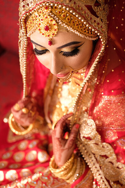 Bride wearing a traditional red sari with gold accessories, embracing cultural elegance and timeless wedding traditions
