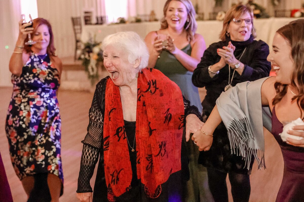 elderly woman in red scarf dances in group at Fort Worth wedding