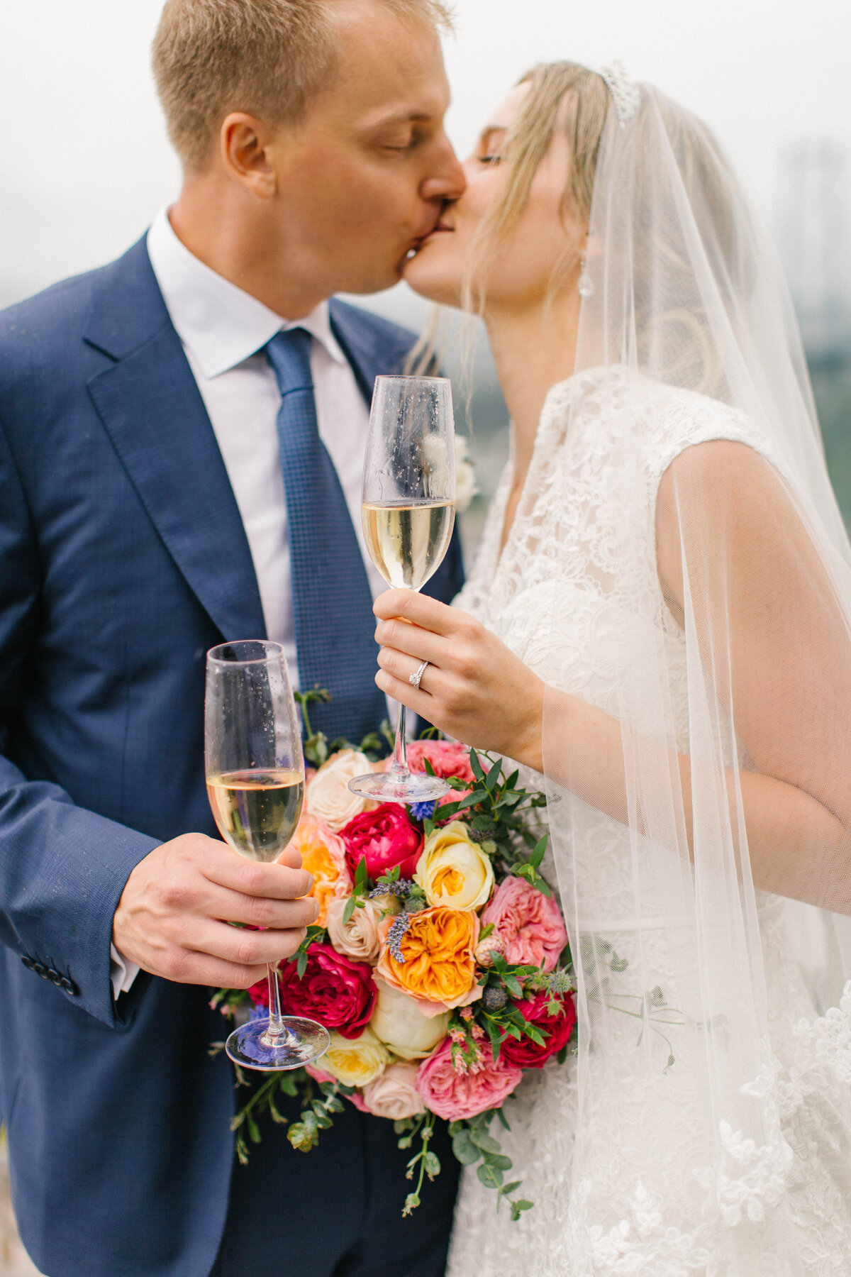 Bride and groom kissing while holding champagne flutes