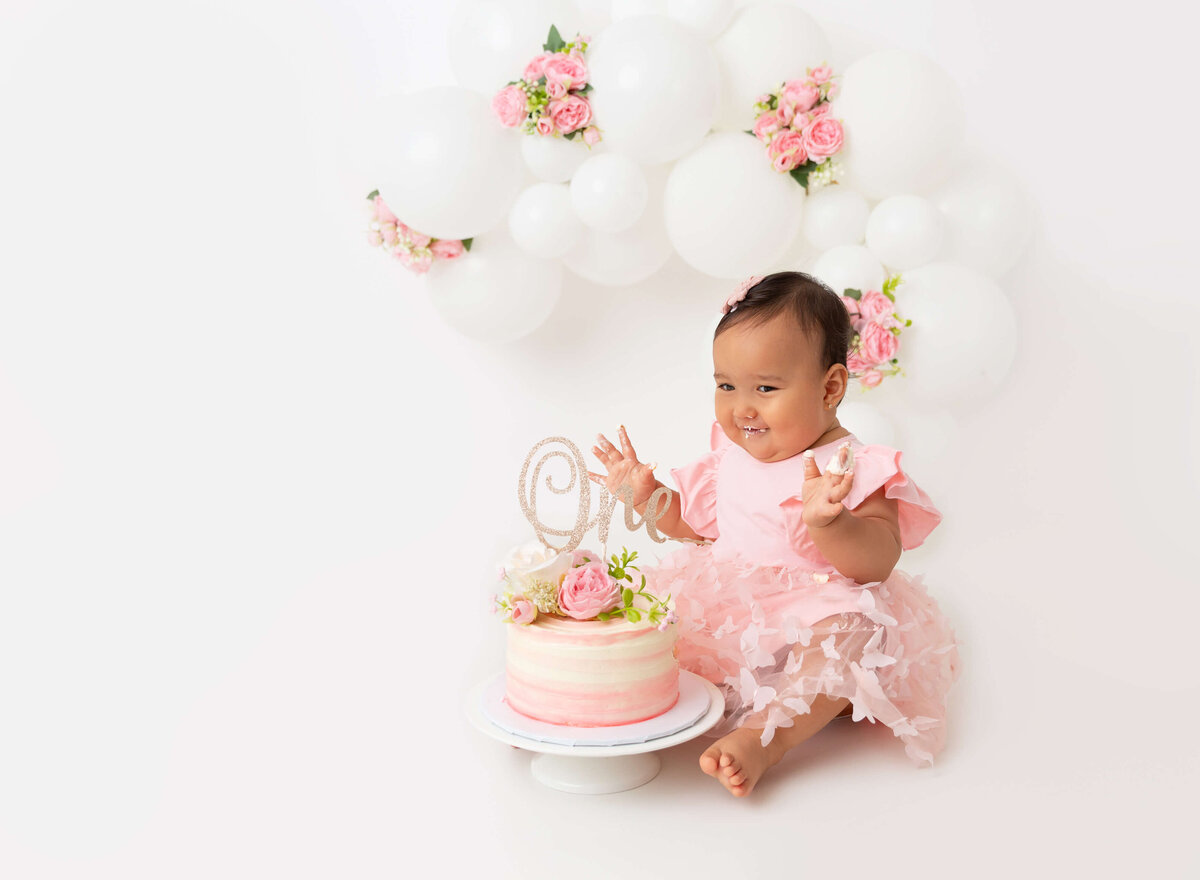 Best Cake smash photographer in Brooklyn, NYC baby girl white with pink flowers balloon garland setup