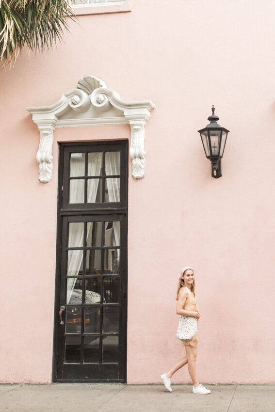 senior girl walking past pink building