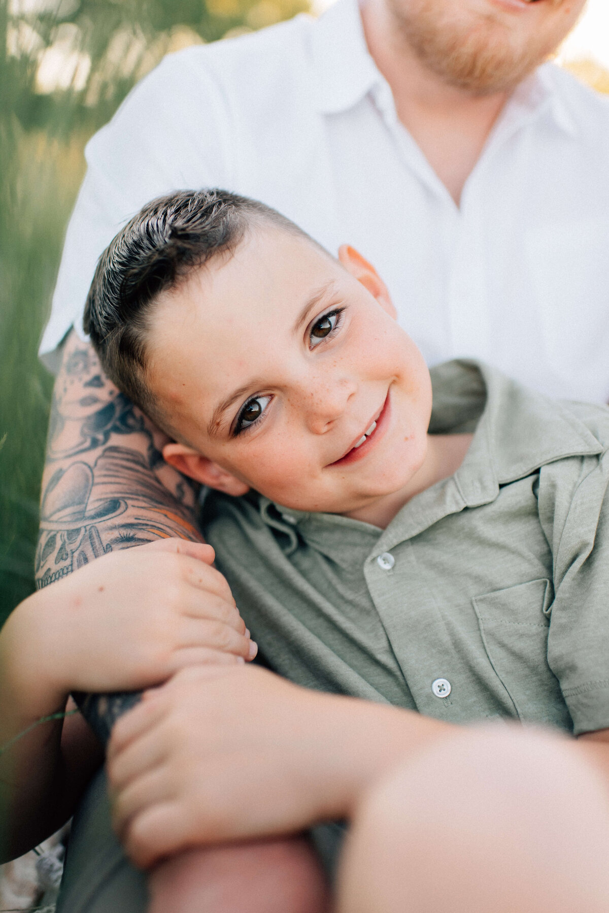 boy sitting in front of dad holding onto his arm with his family