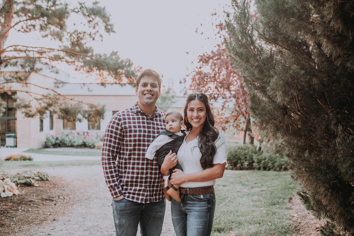 Idaho Falls family photographer captures young family of three with mother, father and baby on Rexburg's BYU campus posing for their family photos
