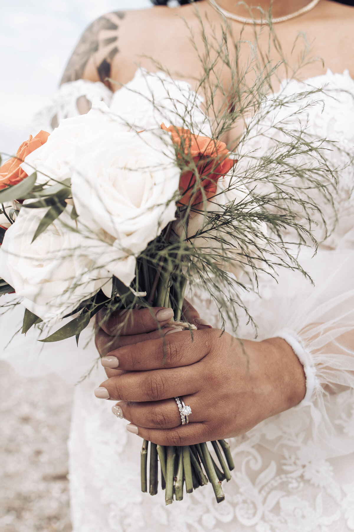 a bride holding an orange and white flower bouquet