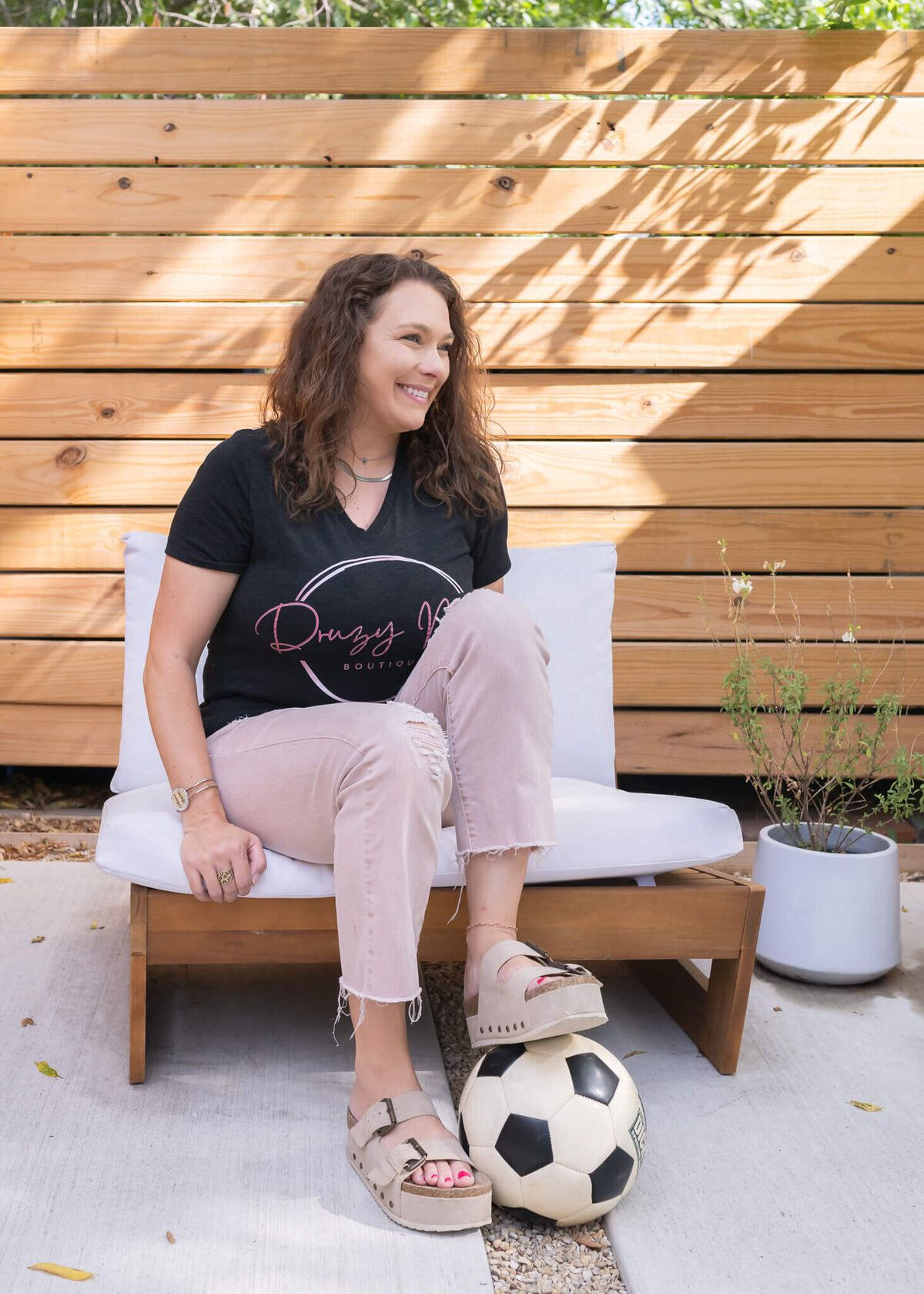 soccer mom boutique owner outside with foot on soccer ball