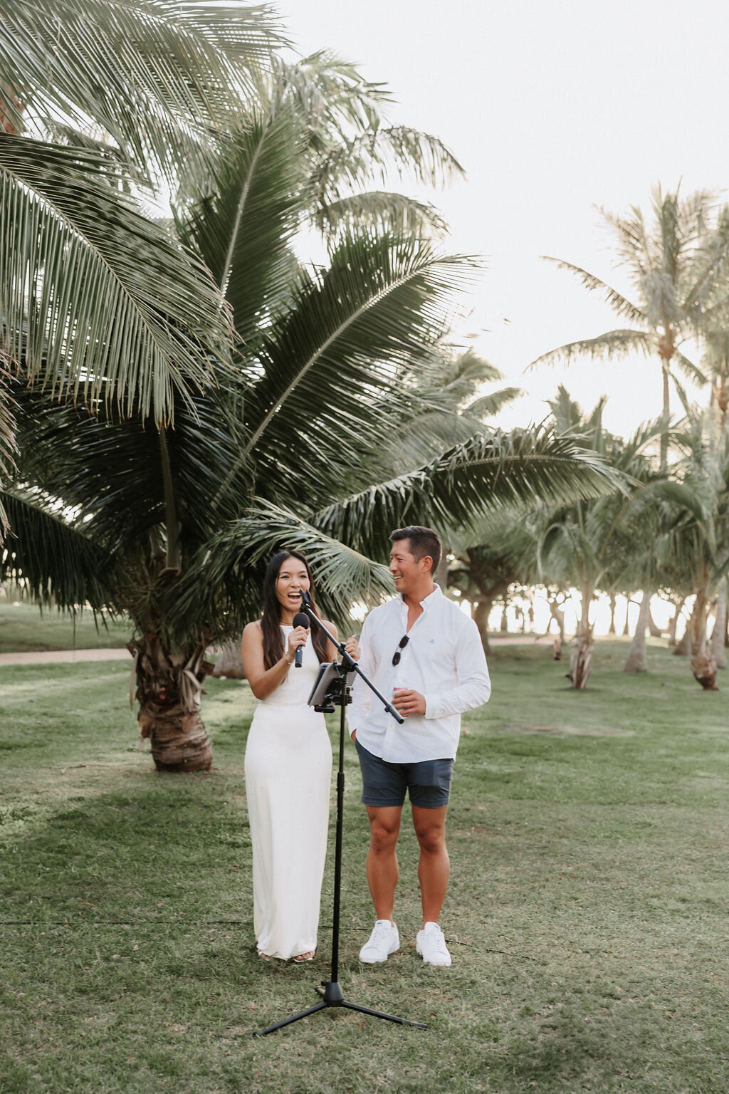 wedding couple making a speech at their welcome dinner at the park surrounded by palm trees