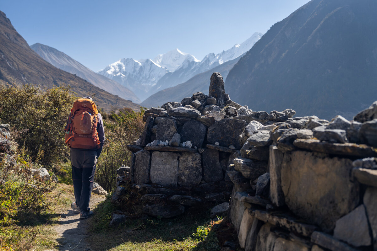 A backpacker trekking next to ancient mani stones through the Langtang Valley in Nepal.