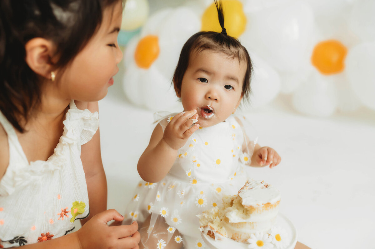 Older siblings help baby dig into birthday cake during Cake Smash Photoshoot in Asheville, NC.